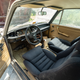 a photo of the tan interior of a long-abandoned 1974 bmw2002tii. the carpet and door upholstery is faded tan; the seats, steering wheel and dashboard are all faded black. there is random trash in the car, which has sat abandoned in a florida field for 25 years
